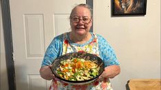 an older woman holding a plate of food in her hands