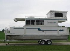 a white houseboat parked on the side of a road in front of a green field