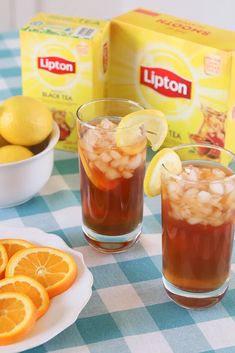 two glasses filled with iced tea and lemons on a table next to boxes of lipton