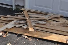 a pile of wood sitting on the ground next to a garage door