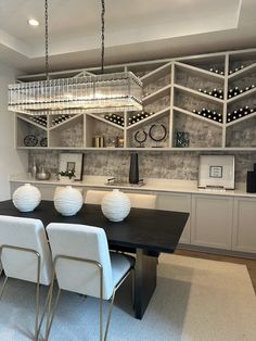 a dining room table with four chairs and a wine rack in the back wall behind it