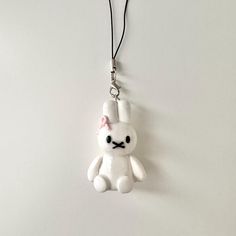 a white stuffed animal with a pink bow on it's head hanging from a cord