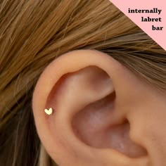 a woman's ear with a tiny gold heart on it