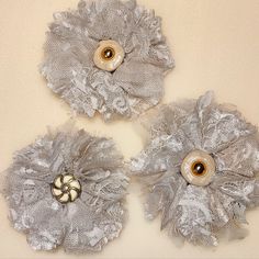 three silver flower brooches sitting on top of a table