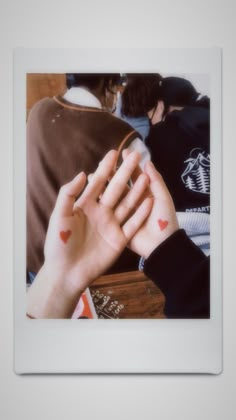 two hands holding each other in front of a white frame with red hearts on it