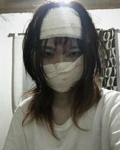 a woman with tape on her face is looking at the camera