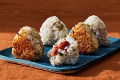 four rice balls on a blue plate with sauce and seasoning sprinkles