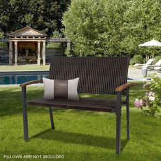 an outdoor bench sitting on top of a lush green field next to a swimming pool