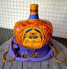 an old fashioned crown royal bottle on a wooden table with blue and yellow ribbon around it