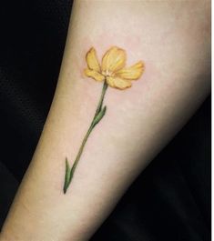 a small yellow flower tattoo on the arm