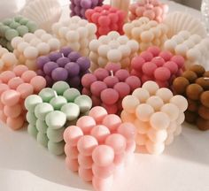 there are many different colored candles in the shape of flowers on top of a table