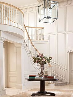 a vase with flowers sitting on top of a table in front of a spiral staircase