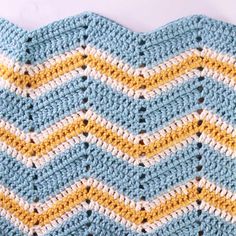 a crocheted blue and yellow blanket is laying on the floor