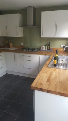 a kitchen with white cabinets and wooden counter tops, black tile flooring and gray tiles