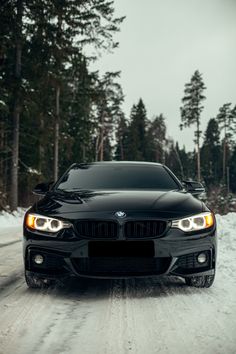 a black car driving down a snow covered road