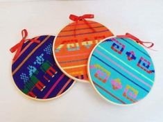 three colorful embroidered ornaments on white surface