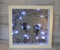 an illuminated shadow box with two fairy tinkerbells