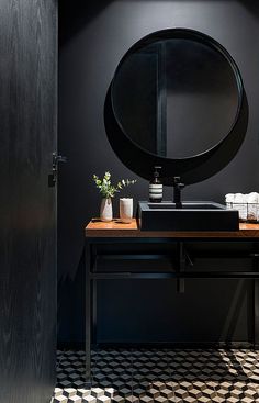 a bathroom with a round mirror on the wall next to a sink and counter top