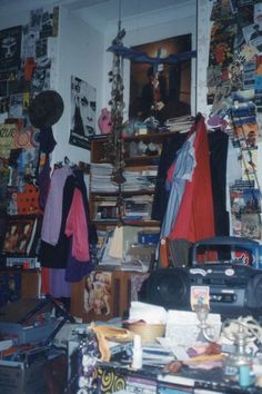 a room filled with lots of clutter next to a wall covered in posters and pictures