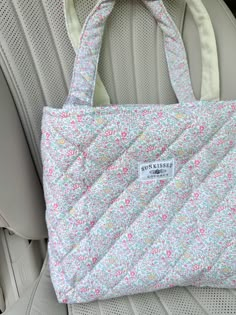 a purse sitting on top of a car seat in the back seat with it's handles down