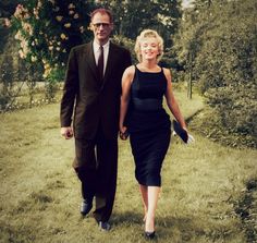 a man and woman are walking in the grass holding hands, both dressed in black