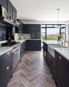 a large kitchen with wooden floors and black cabinetry, along with white counter tops