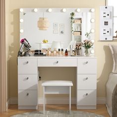 a white vanity with lights on it next to a bed and a chair in a room