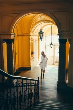 a woman is walking down the stairs in an old building with light coming through it