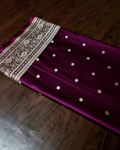 a purple and white dress laying on top of a wooden floor next to a table