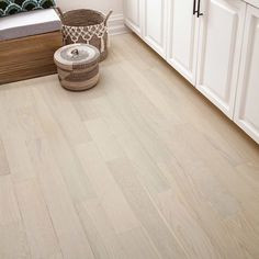 a bathroom with white cabinets and wood flooring, including a basket on the ground