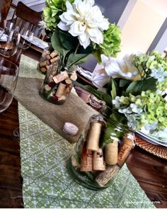 there is a vase filled with flowers and wine corks on the dining room table