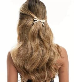 the back of a woman's head with long hair and a bow in it