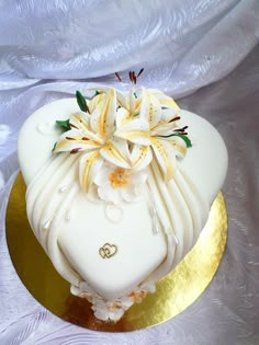 a wedding cake decorated with flowers and gold trimmings on a white table cloth