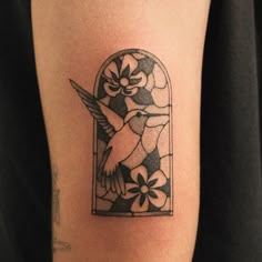 a tattoo on the arm of a woman with a bird and flowers in it's window