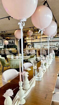 a long table with balloons on top of it in a room filled with chairs and tables