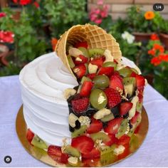 a white cake with fruit on top and waffles in the shape of an ice cream cone