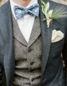 a man in a suit and bow tie with a boutonniere on his lapel