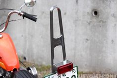 a motorcycle with a license plate attached to it's handlebars is parked in front of a concrete wall