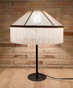 a lamp that is on top of a wooden table next to a brick wall and floor