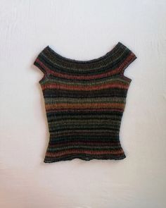 a knitted sweater hanging up on a white wall next to a pair of scissors