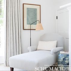 a living room with a white couch, chair and lamp on the wall next to a window