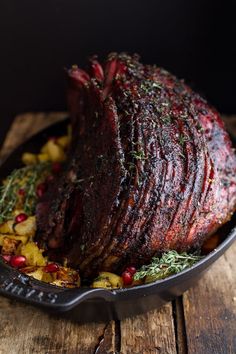 a roasting pan filled with meat and vegetables on top of a wooden table next to a fork