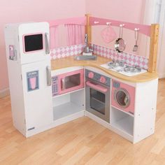 a pink and white play kitchen with wooden floors