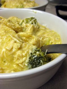 a bowl filled with broccoli and cheese on top of a table next to another bowl