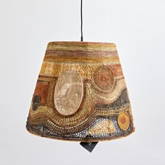 a lamp hanging from the ceiling with an artistic design on it's fabric shade