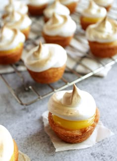 cupcakes with frosting and icing sitting on top of a cooling rack