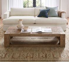 a living room with a couch, coffee table and rug in front of the window