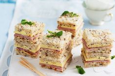 four sandwiches stacked on top of each other with chopsticks next to them and a cup of tea in the background