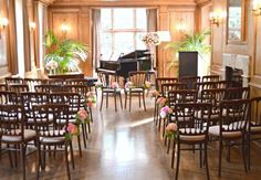 a room filled with lots of wooden chairs and tables covered in pink flowers next to a piano