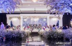 an elaborately decorated stage with flowers and trees in the background at a wedding reception